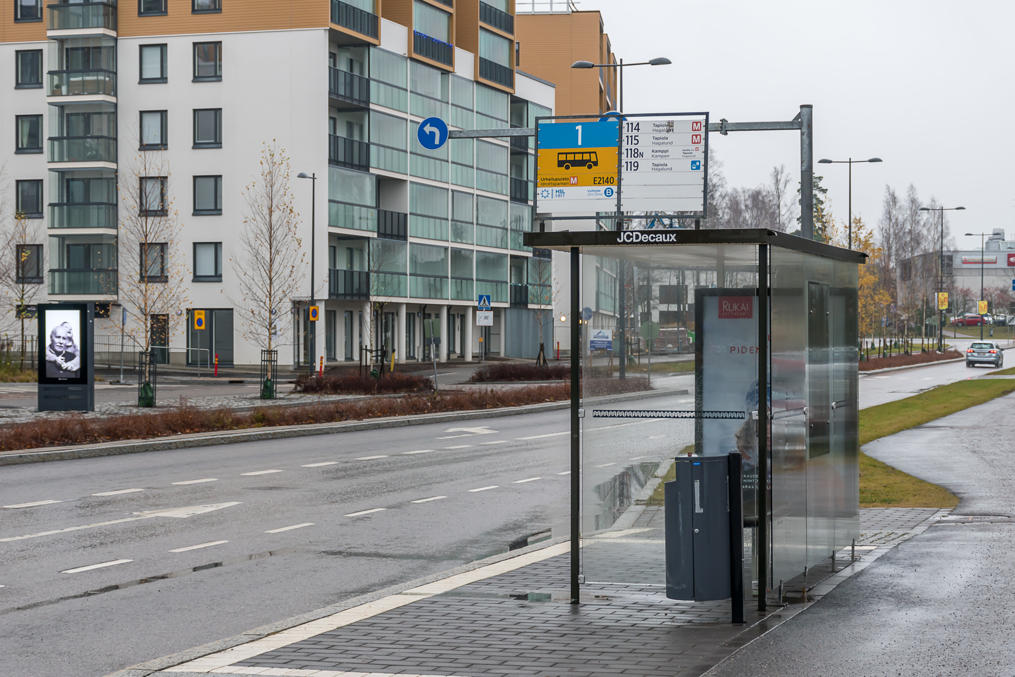 Bus stop.  Note: platform number (1; to look up a specific stop at one place), ticket zone (B), stop overall number (E2140), bus routes with ones going to a metro station (orange M) and neighborhood routes (blue sign) specifically marked