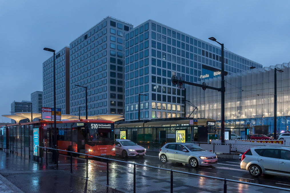 Pasila station public transport hub terminal.  Note a tram and a trunk bus.  The station building is to the right, and tracks are underneath this road.  Mall of Tripla proper is in the center