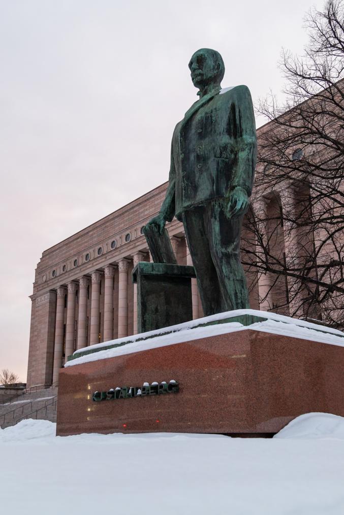 Памятник Стольбергу у здания Парламента Финляндии.  В руке Стольберг держит свод законов.  Источник: Википедия