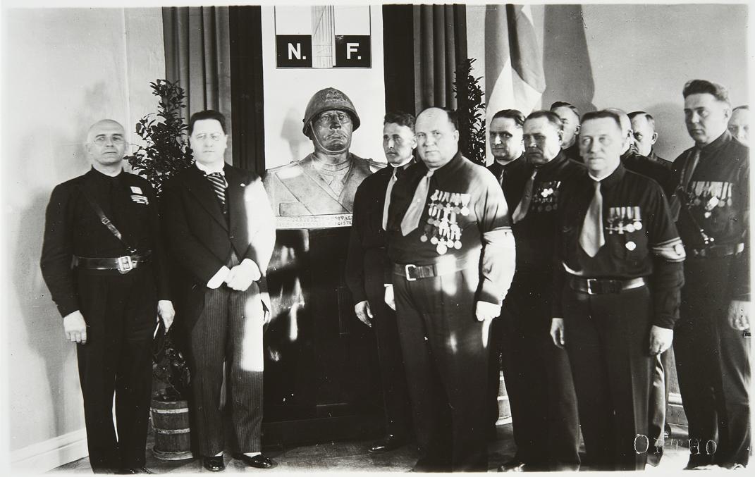 Делегация итальянских фашистов дарит IKL бюст Муссолини, 1935.  Увешанный медалями Косола потолстел и обрюзг.  Фото из вики